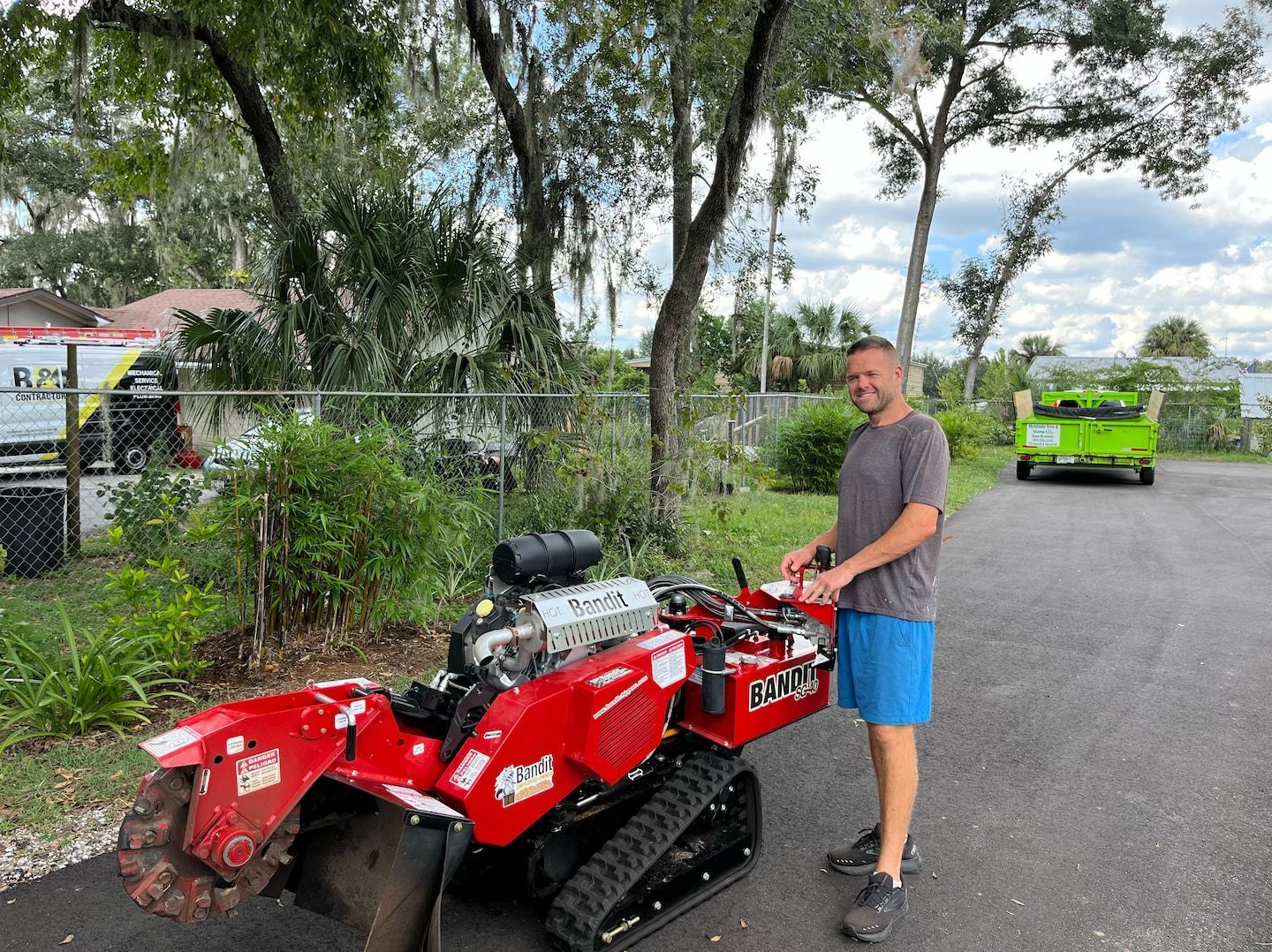 A man is standing next to a red tractor in a parking lot.