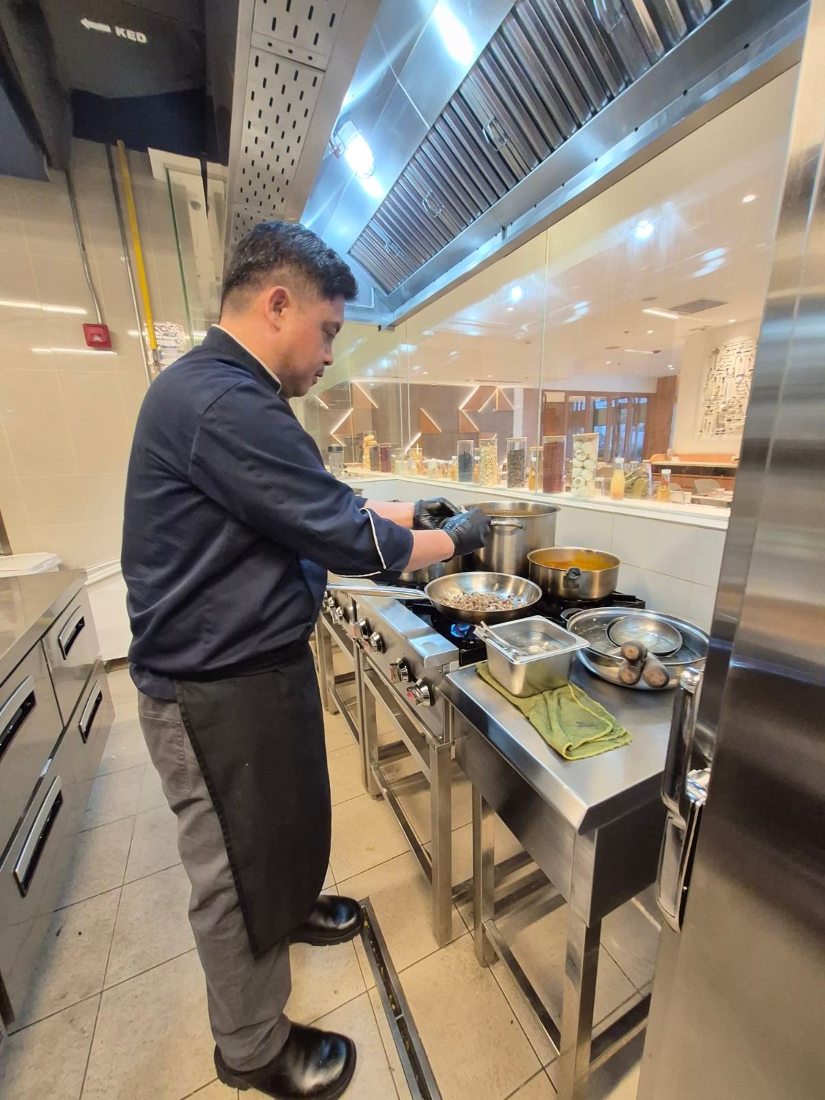 Person serving food at a buffet counter in a bright dining area