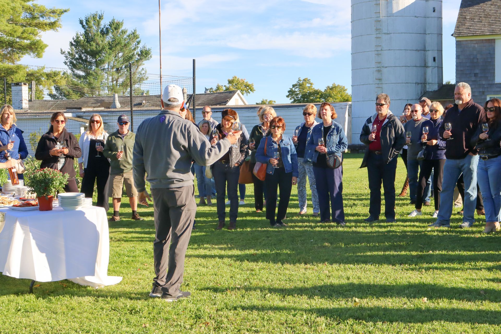 A man is standing in front of a group of people in a grassy field.