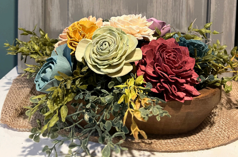 Wooden bowl centerpiece with colorful wooden flowers and greenery.