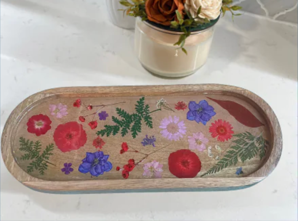 Man and woman smiling, sitting near an easel with a painting, likely indoors.