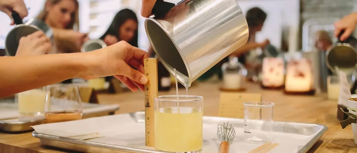 A small, handmade felt cat figure with white fur, grey patches, a grey tail, and a tiny pink nose on a white background.