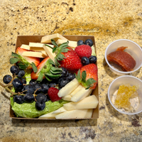 A box filled with fruits and cheese is on a counter.