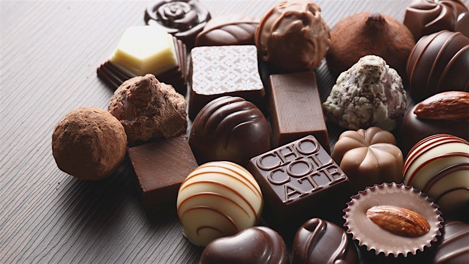 Assorted chocolates, various shapes and textures, arranged on a dark surface.