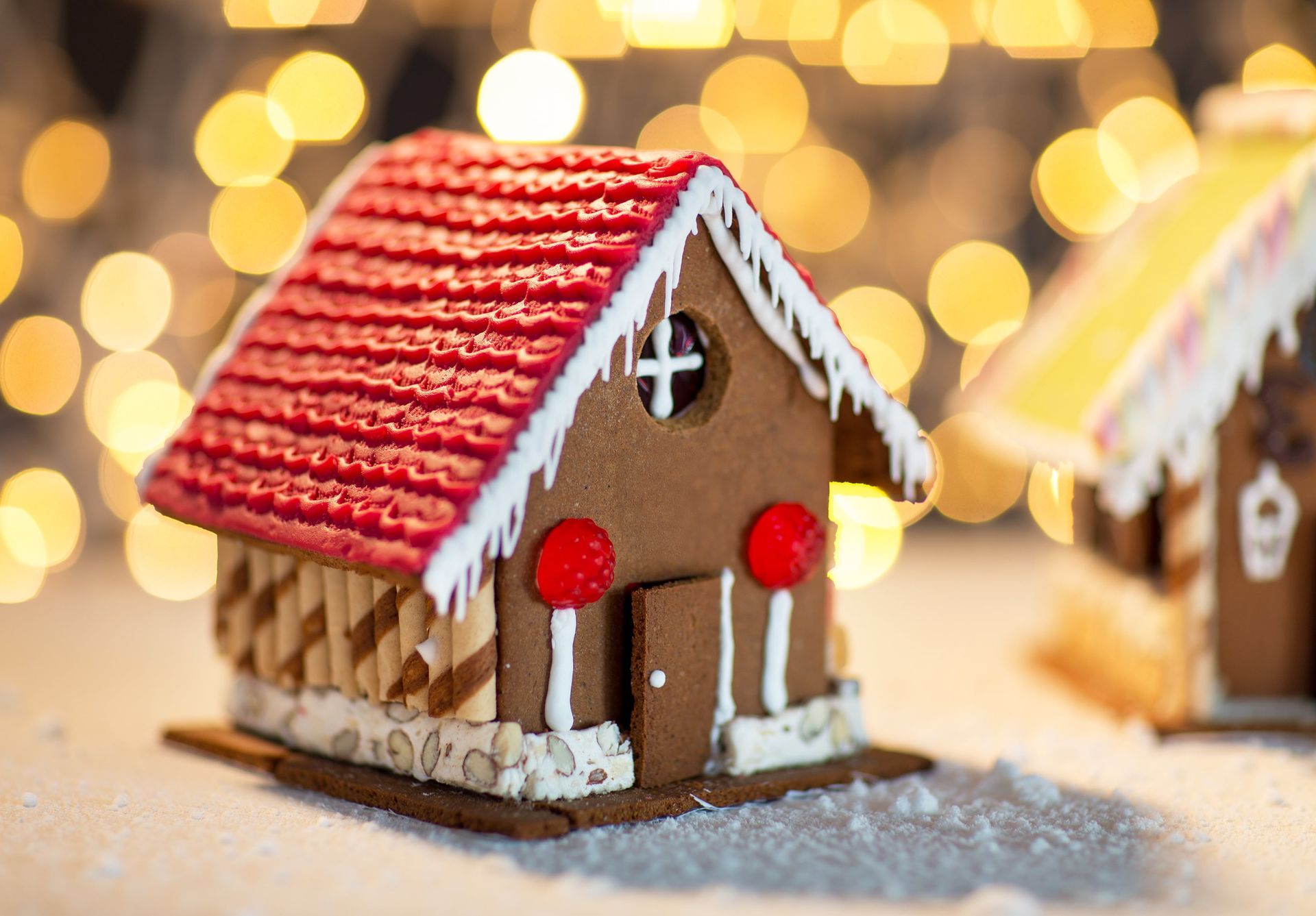 Gingerbread house with red roof, white icing accents, and red candy decorations.