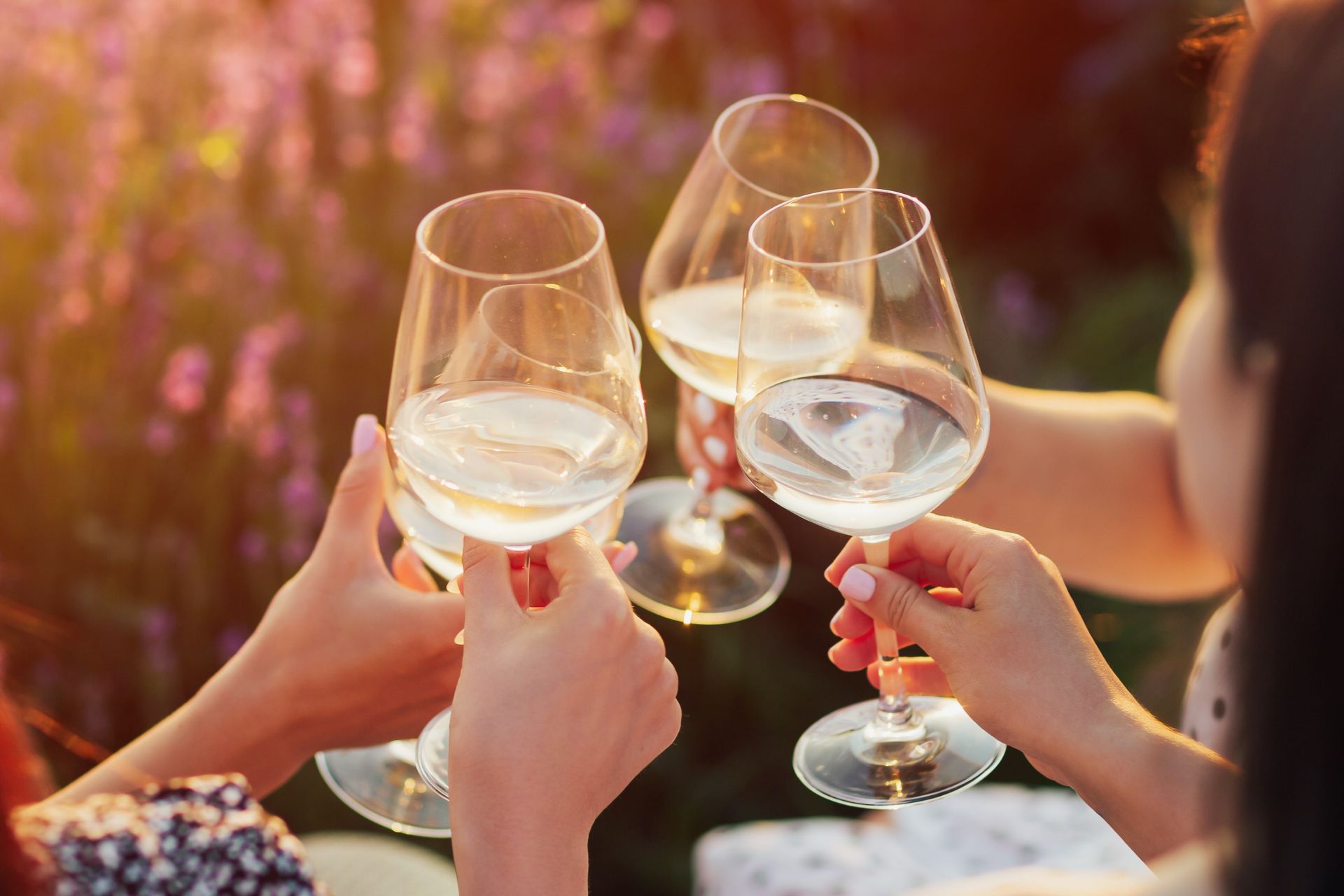 People toasting with wine glasses in a field of purple flowers.