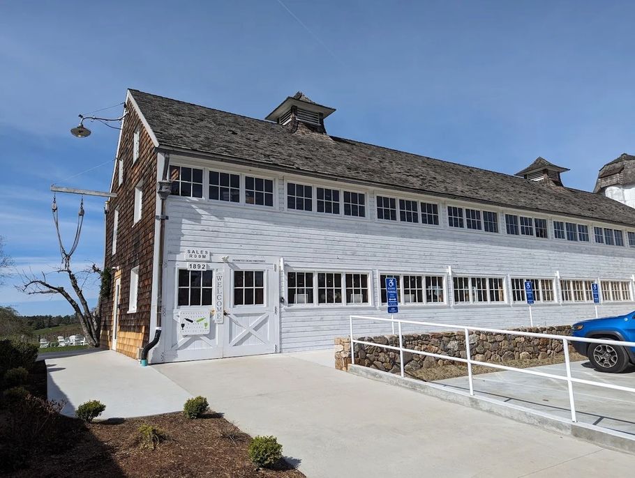 A large white barn with a blue car parked in front of it