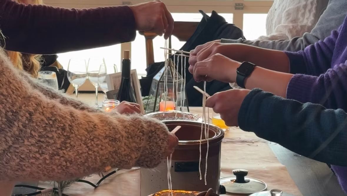 People dipping food into a fondue pot, held by skewers, at a table.