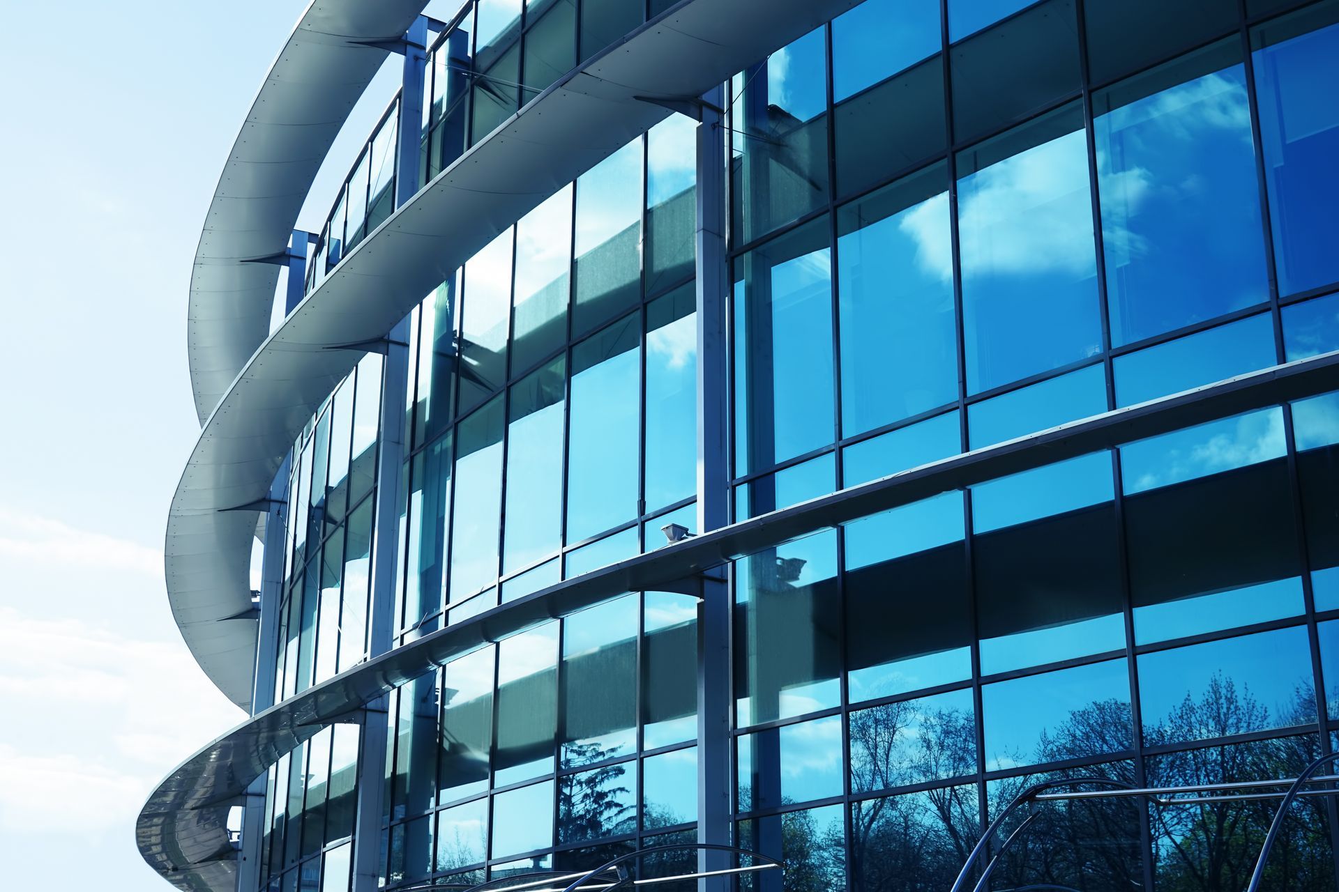 Curved glass office building facade with blue reflective windows and white exterior accents