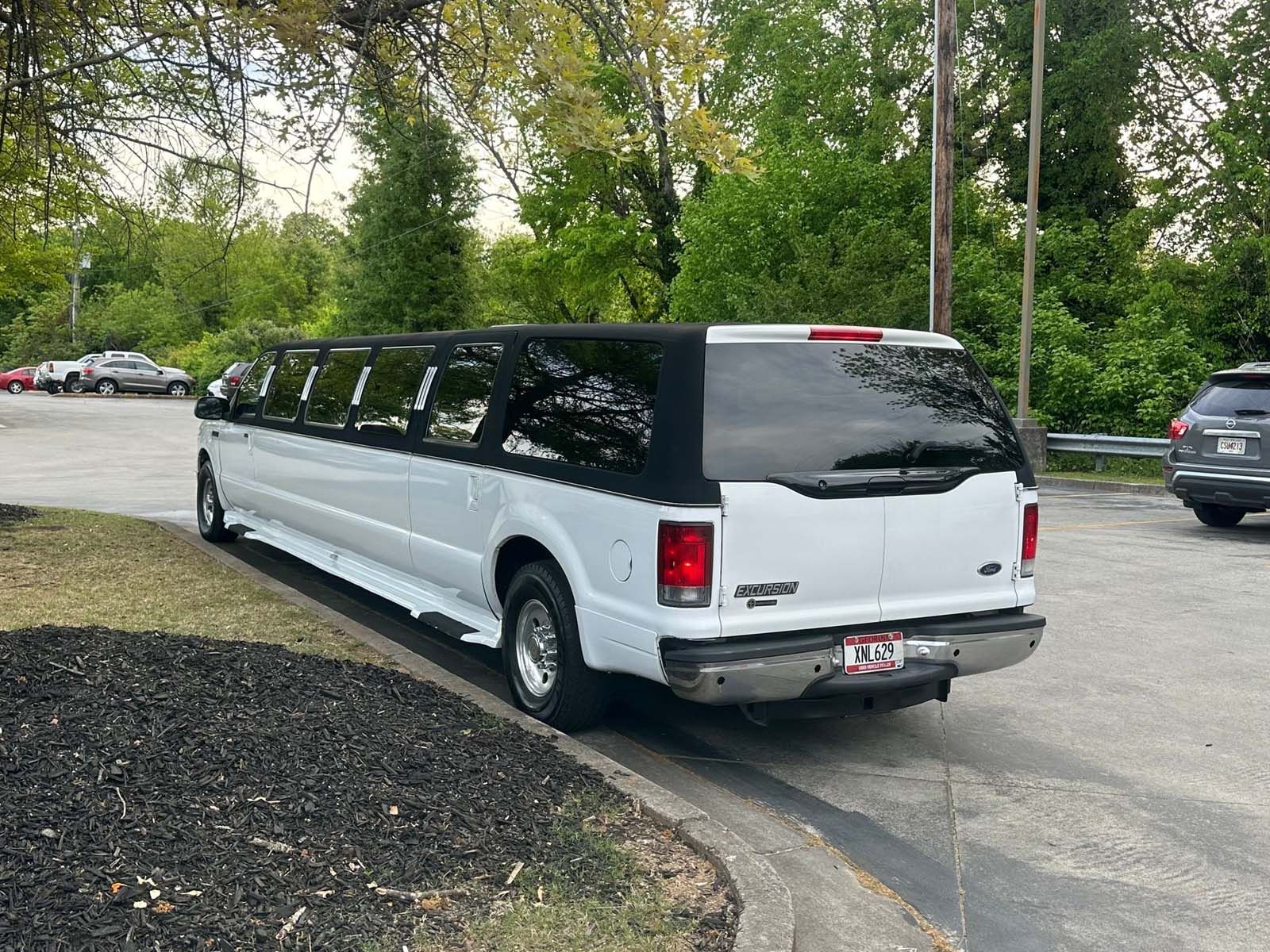 A white limousine is parked in a parking lot.