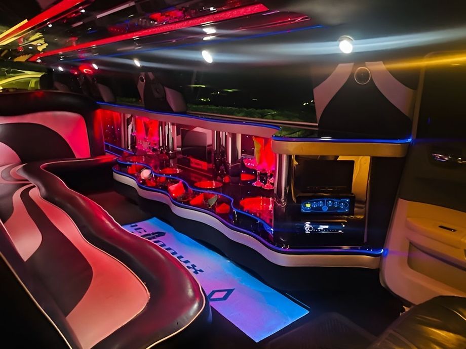 Luxury limo interior with red and blue LED lighting, leather seats, and a bar area