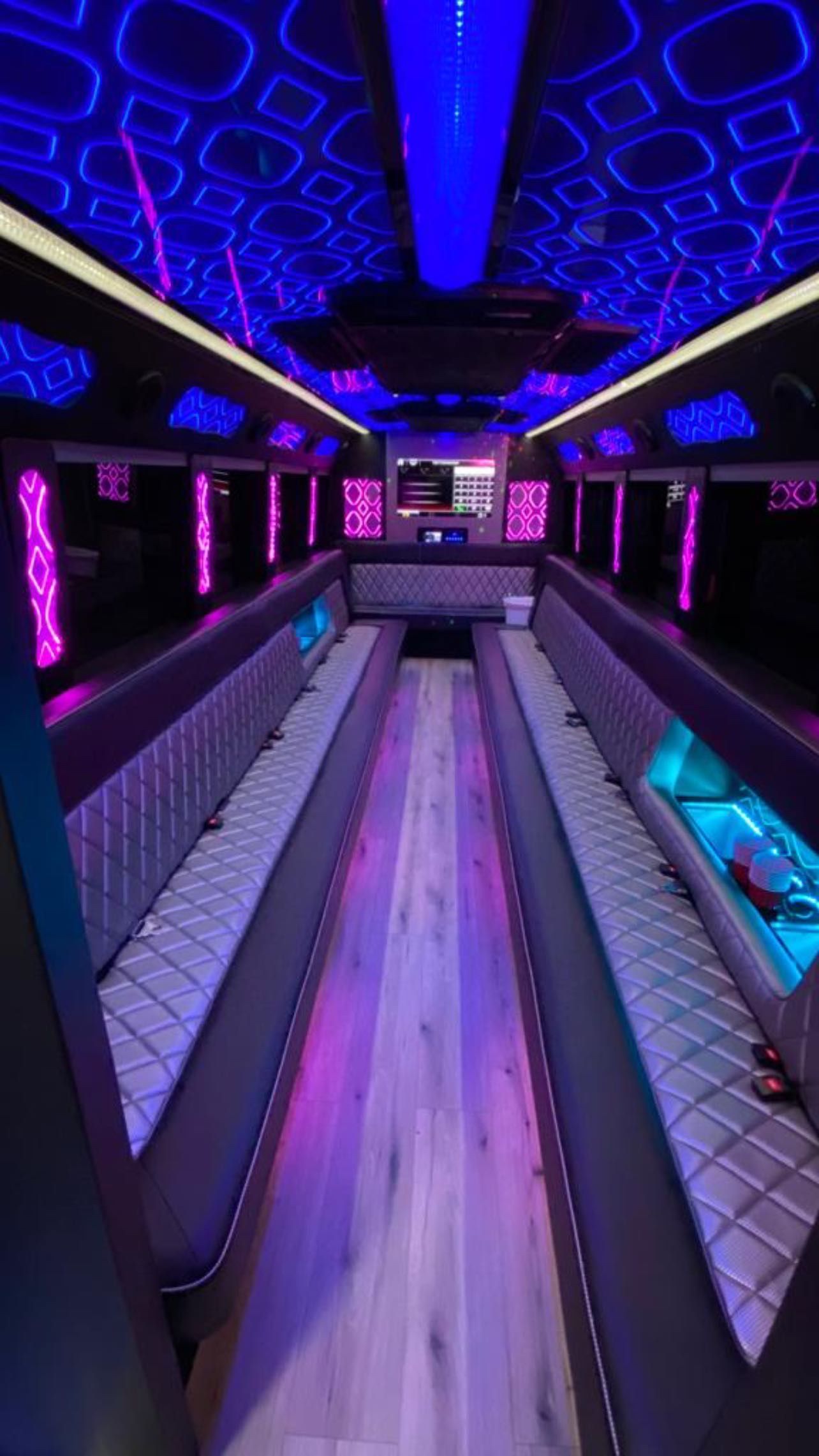 Empty luxury party bus interior with purple and blue LED lighting and long bench seating