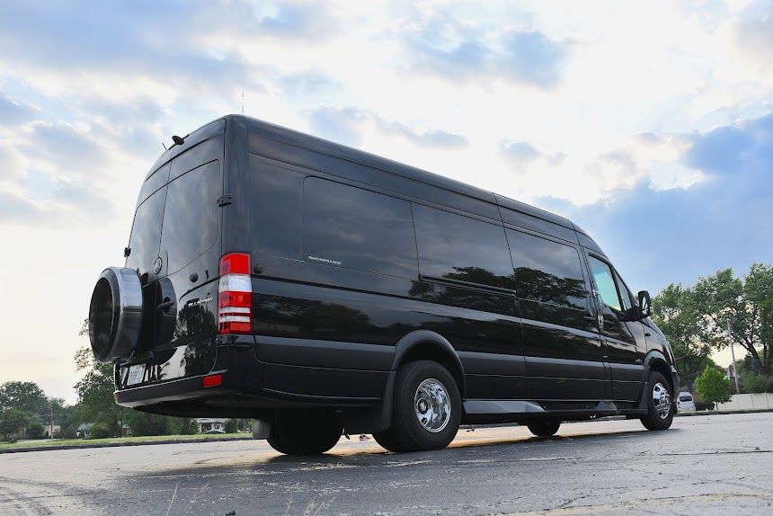 Black extended van parked on pavement under a cloudy sky, rear three-quarter view
