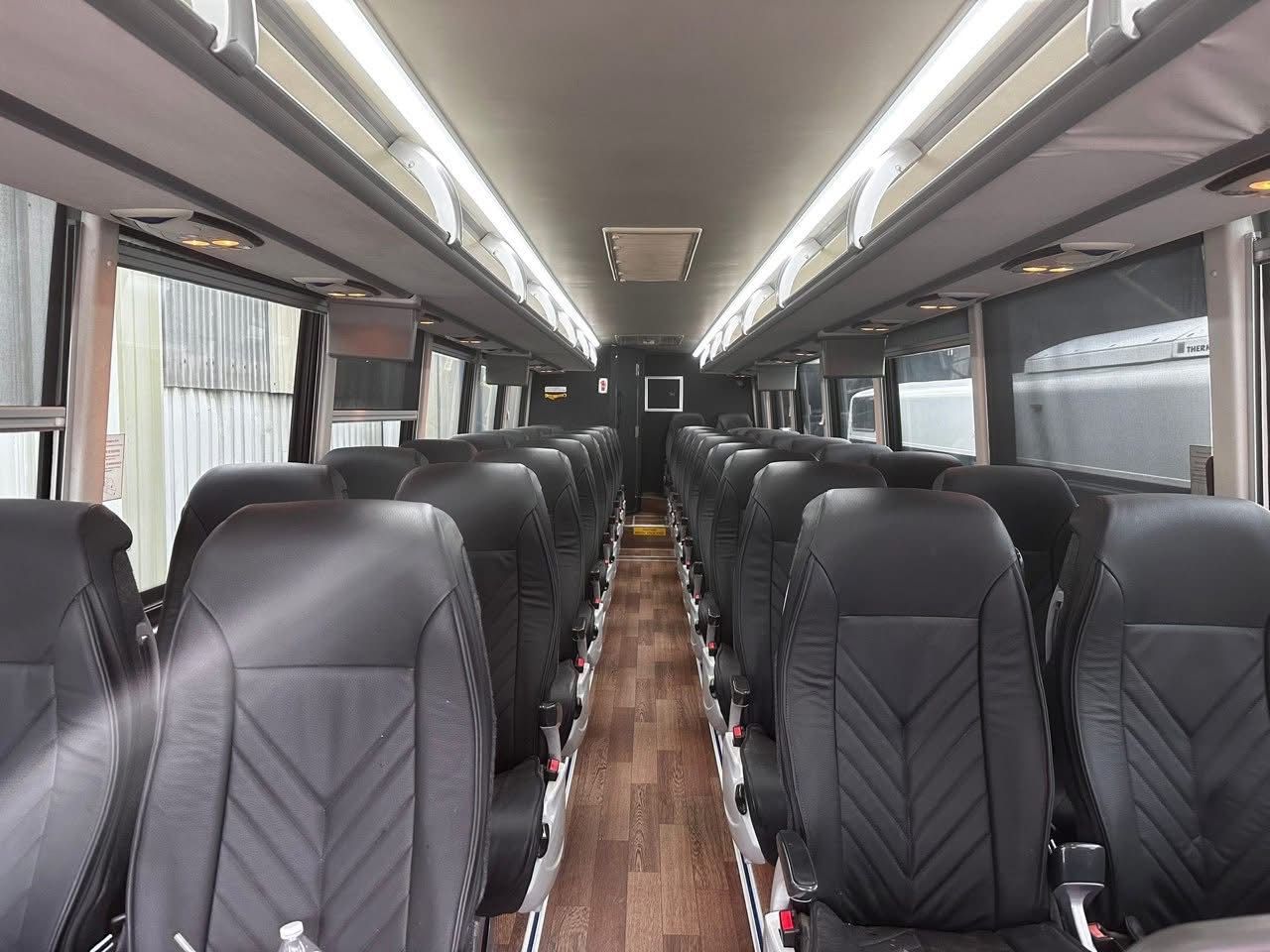 Empty modern bus interior with black seats and wood-pattern aisle flooring