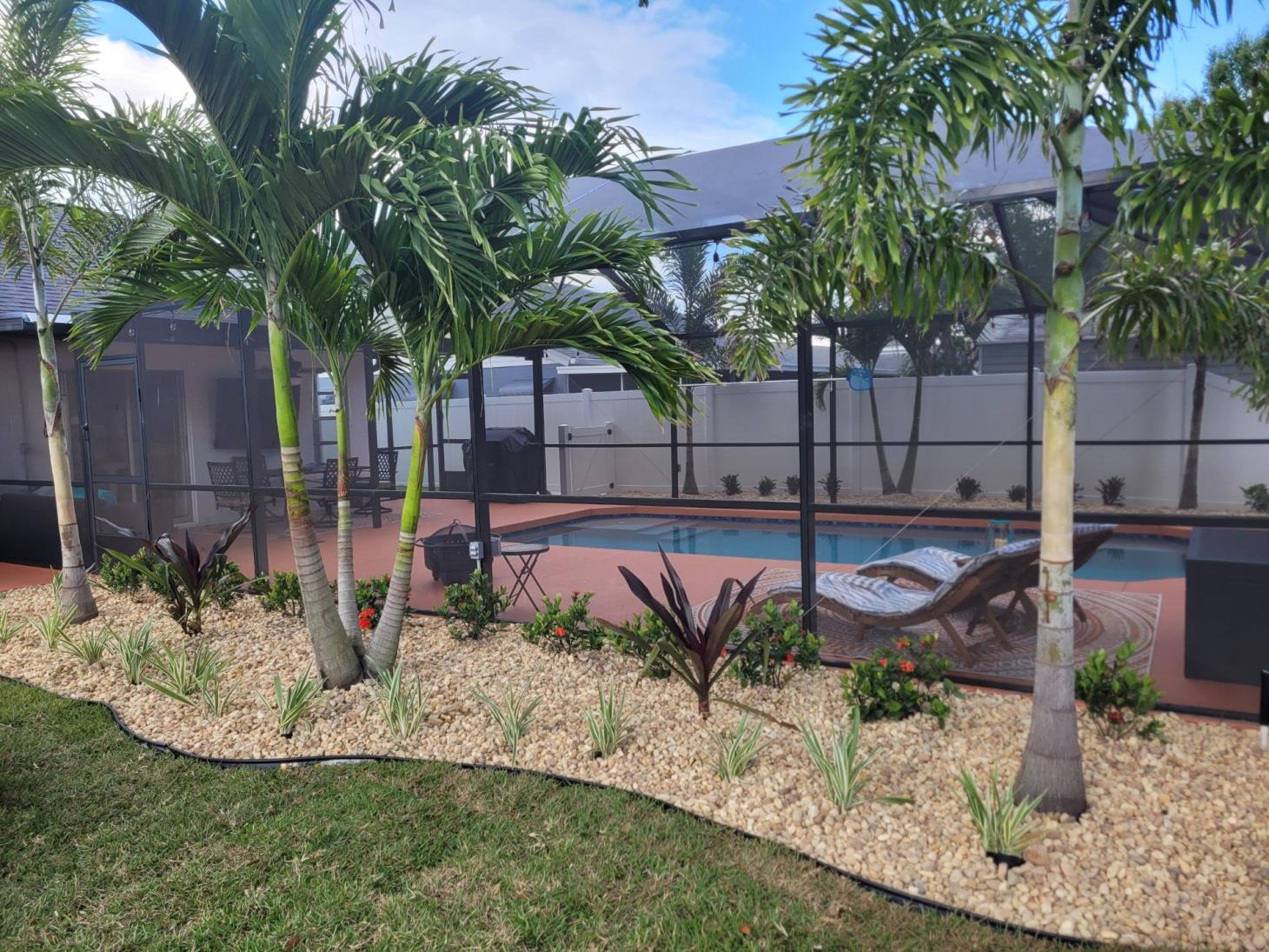 There is a swimming pool in the backyard of a house surrounded by palm trees.