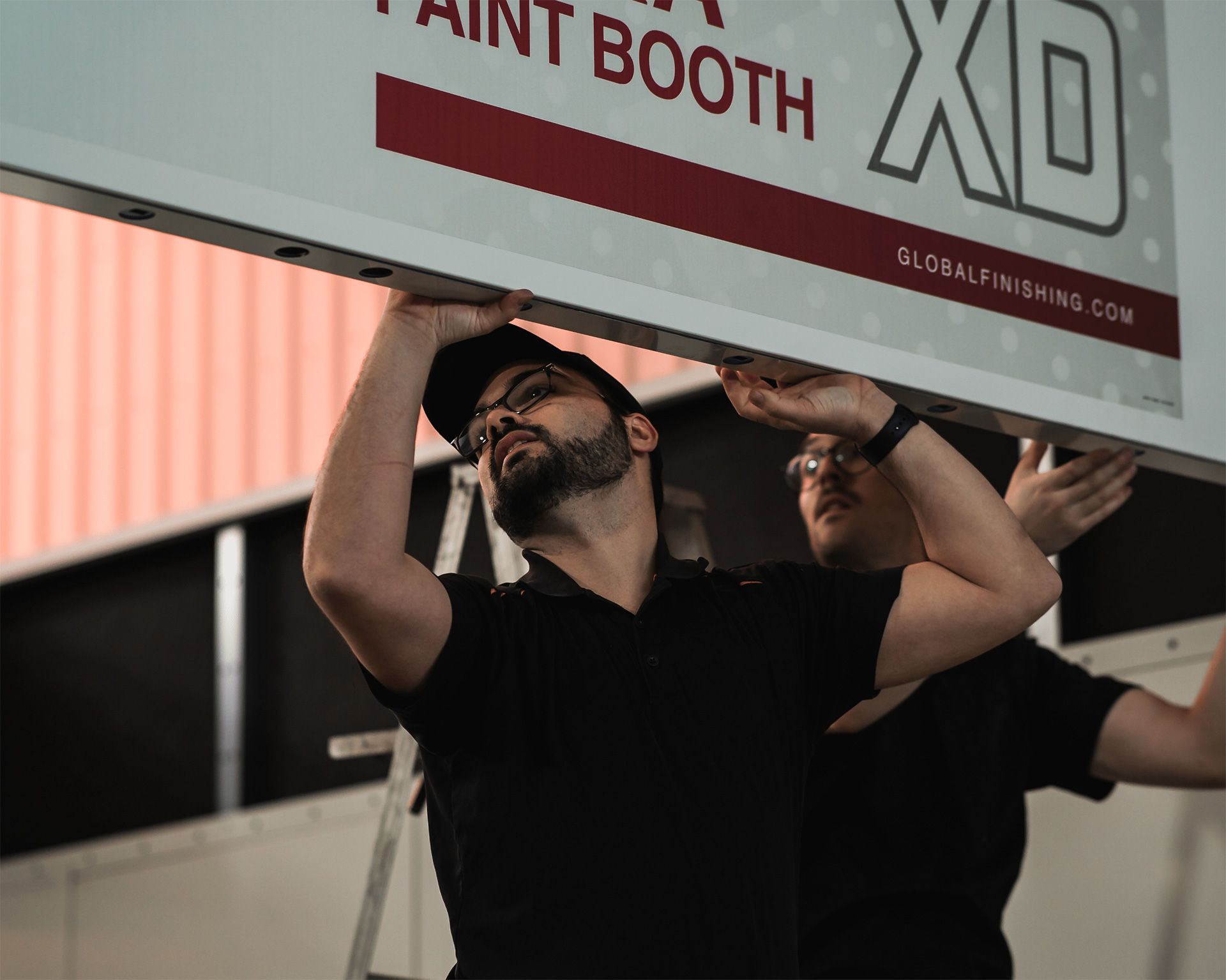 Deux hommes travaillent sur un panneau indiquant cabine de peinture xd.