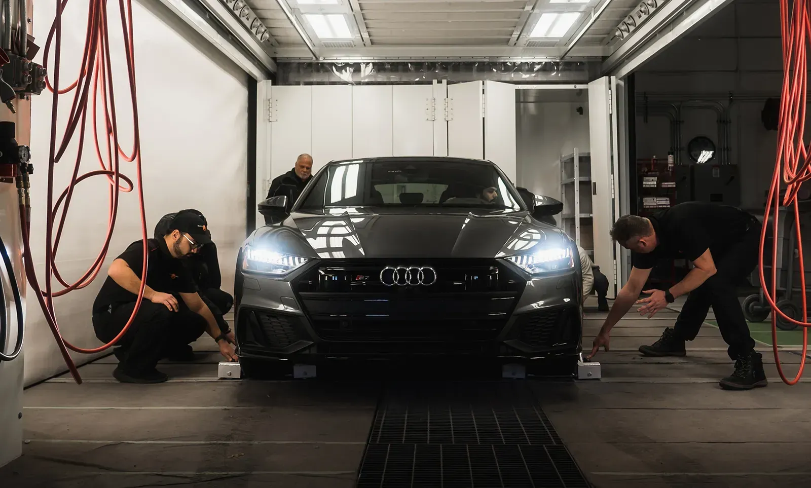 Un groupe d'hommes travaille sur une voiture dans un garage.