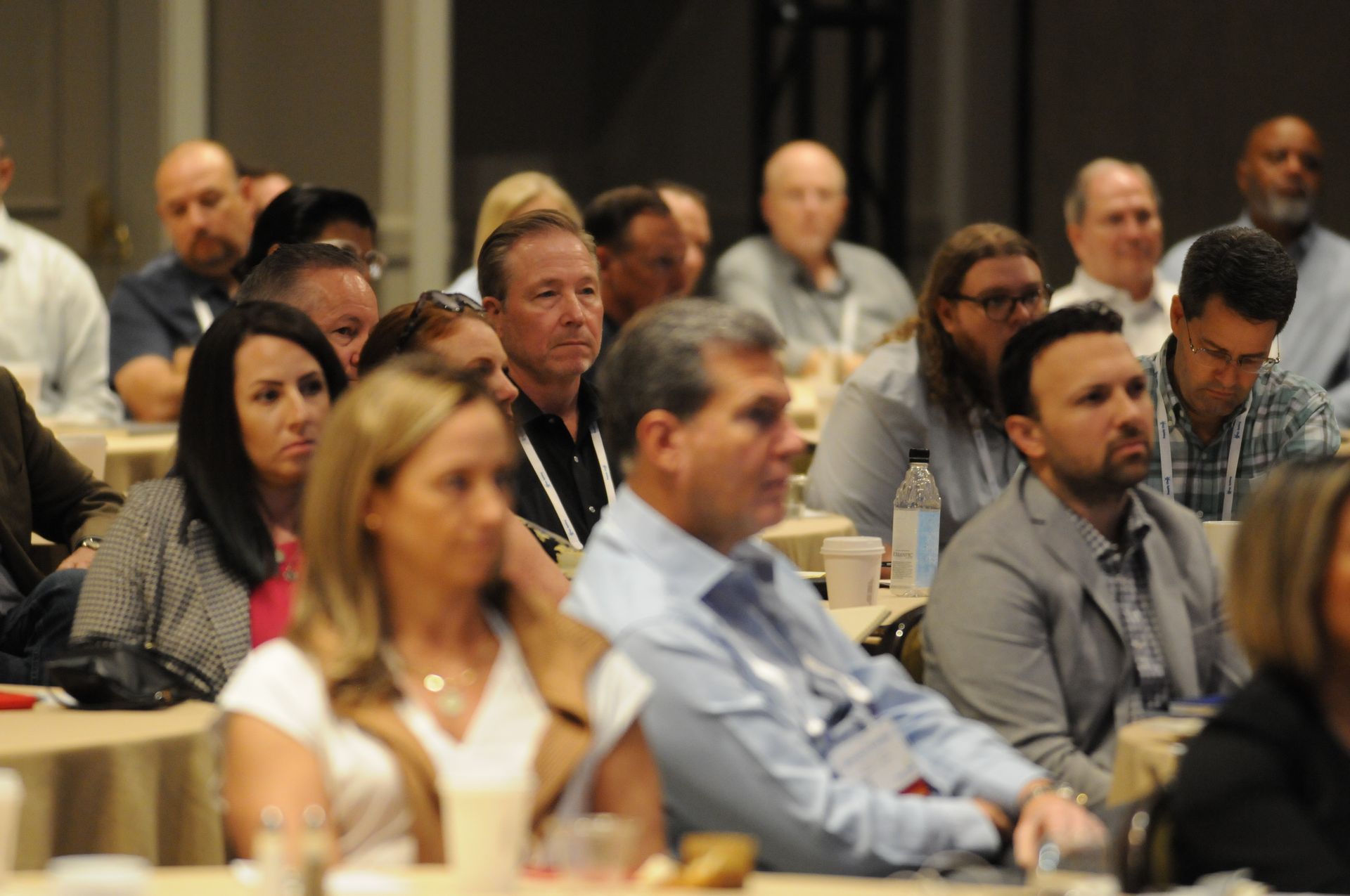 Audience at conference, focused on speaker, diverse group in a large room.