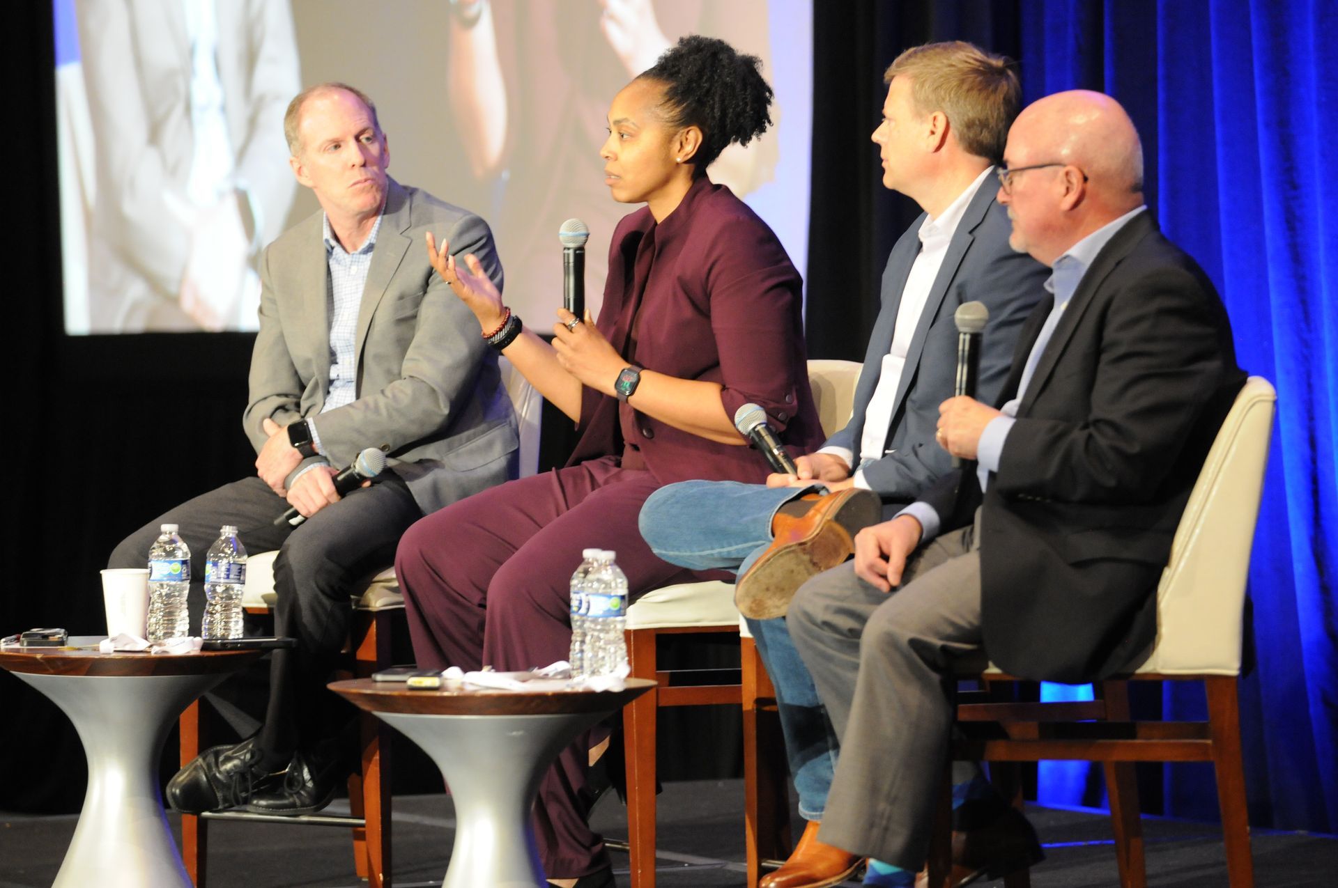 Panel of four people on stage, speaking into microphones.
