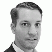 Man in blazer, looking directly at the viewer with a neutral expression. Black and white headshot.