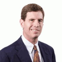 Man in suit smiles, brown hair, white background.