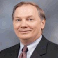 Man with short brown hair and suit, smiling slightly, looking at the camera.