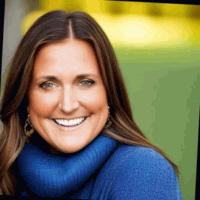 Woman with brown hair smiles wearing a blue sweater, with green background.