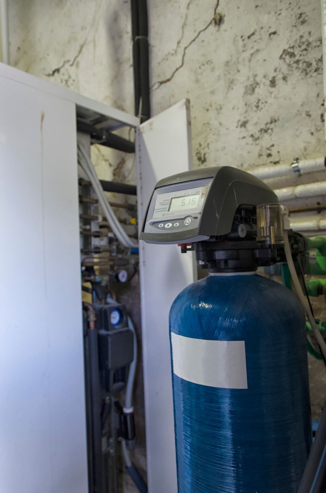 A blue water filter is sitting in a room next to a wall.