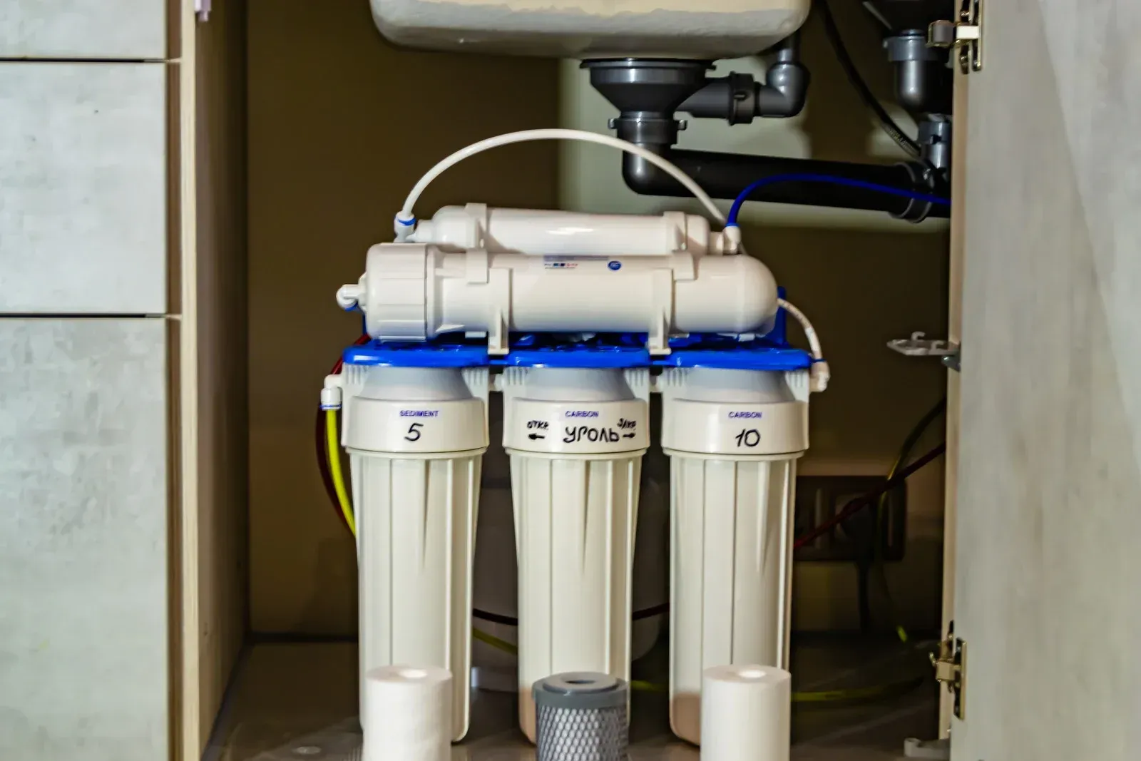 Reverse osmosis water filter system installed under a sink. White and blue components with pipes.