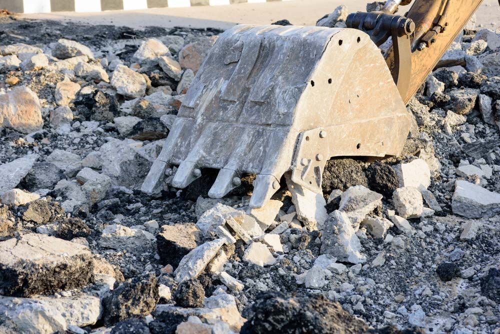 Large Excavator Bucket is Sitting on Top of a Pile of Rocks — On Demand Diggers & Demolitions in Molendinar, QLD