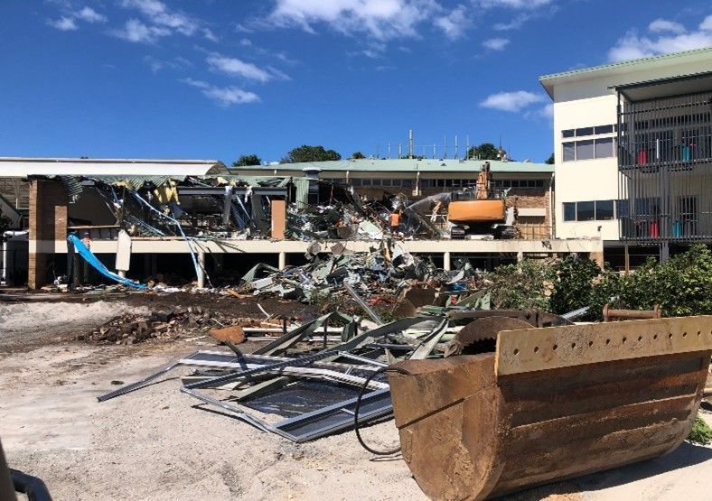 Large Bucket is Sitting in Front of a Building That is Being Demolished — On Demand Diggers & Demolitions in Gold Coast, QLD