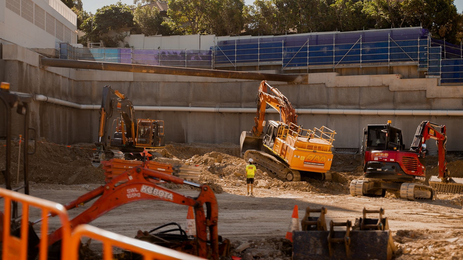 Construction Site With Excavators, a Worker, and Retaining Walls — On Demand Diggers and Demolitions in Molendinar, QLD