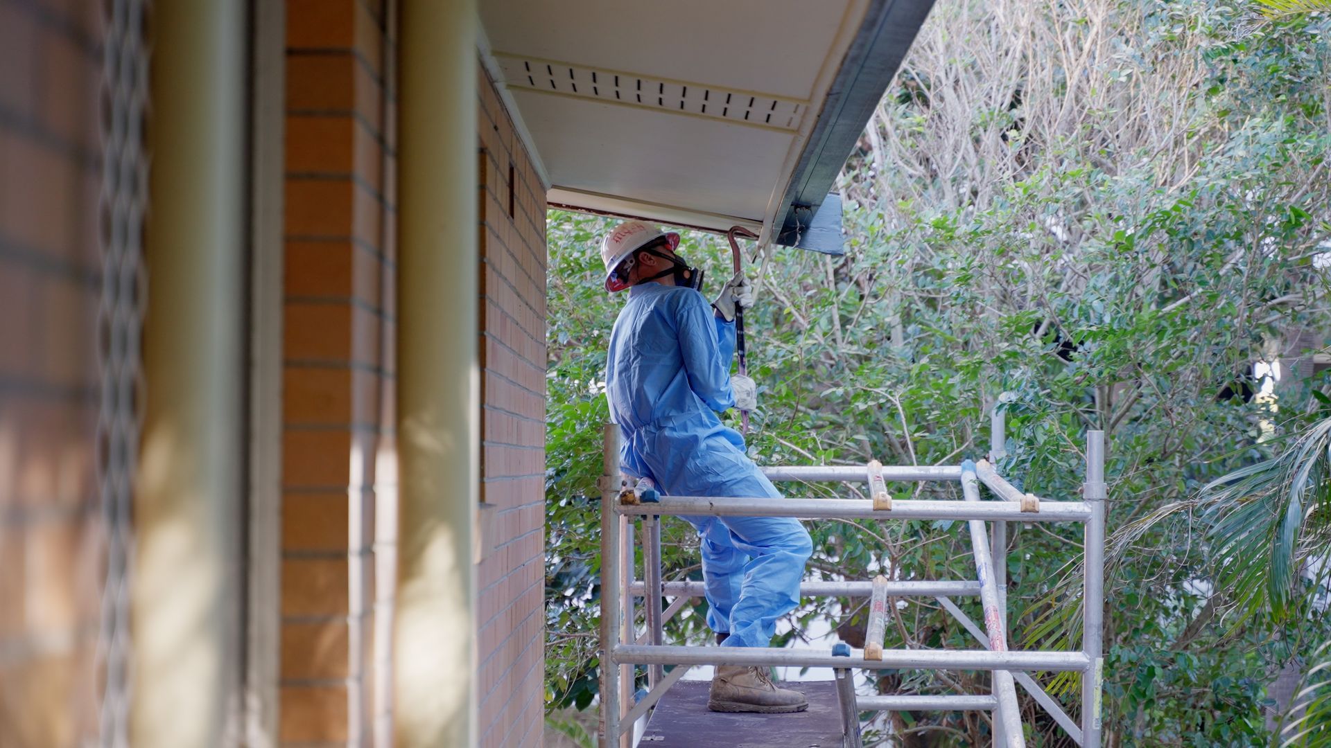 Man is Spraying Red Paint on a Pile of Wood — On Demand Diggers & Demolitions in Molendinar, QLD
