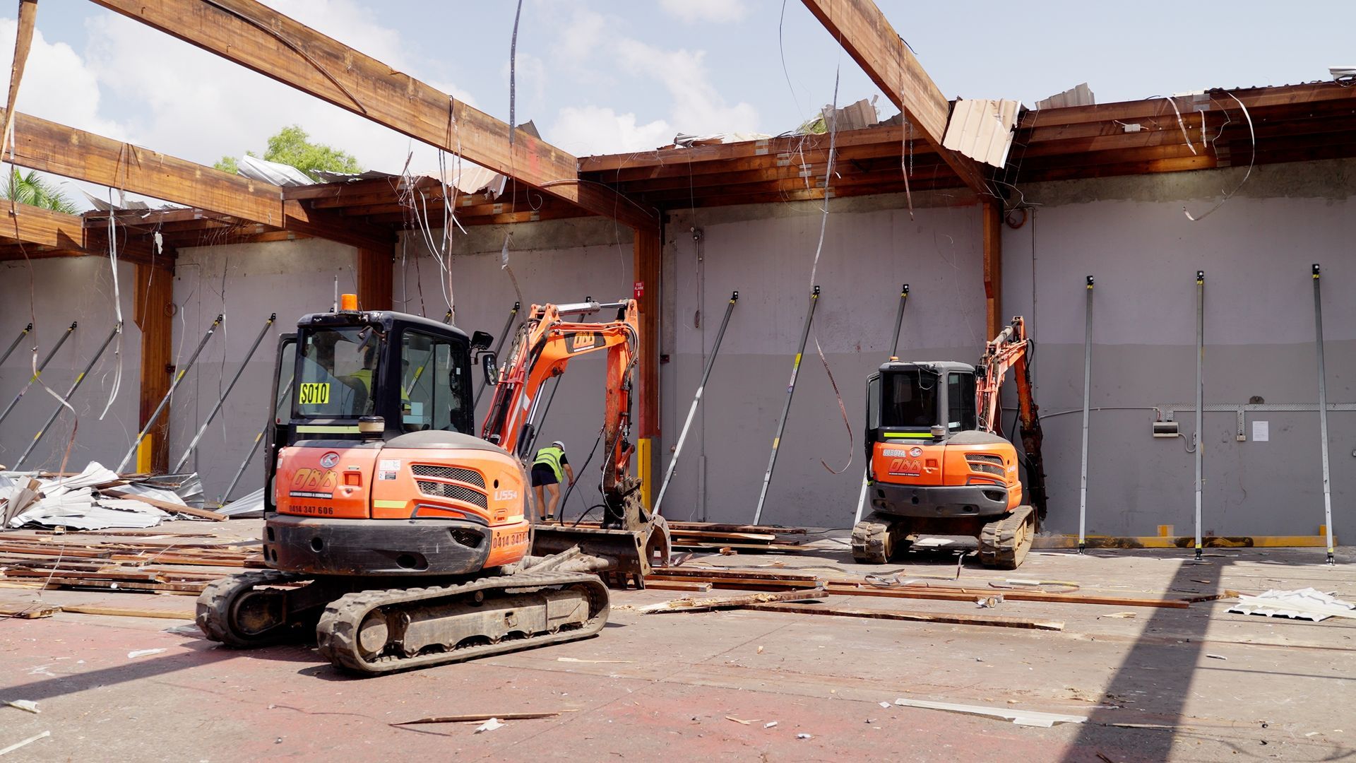 Yellow Excavator Demolishing A Brick Building — On Demand Diggers & Demolitions in Molendinar, QLD