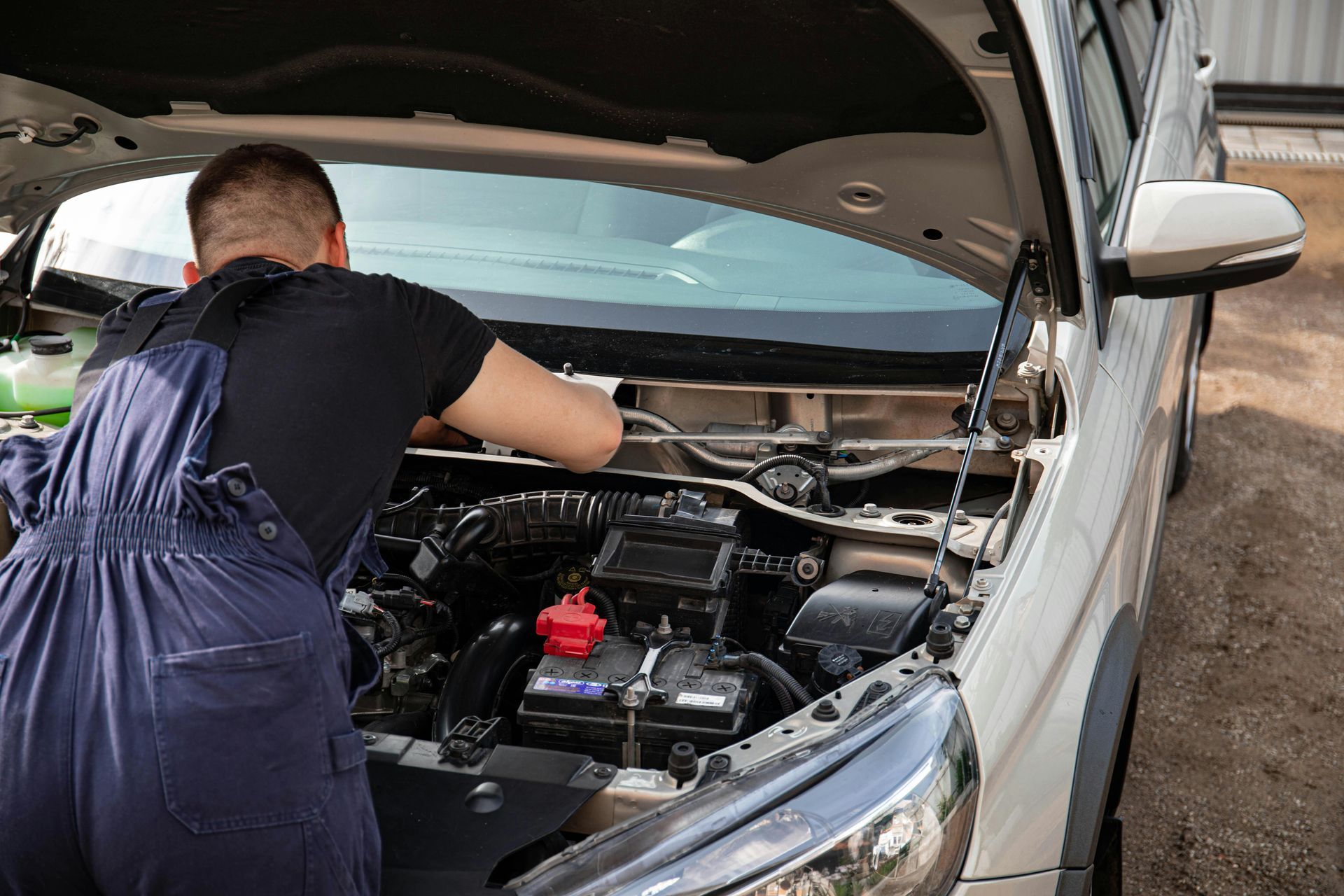 Un hombre está trabajando en el motor de un coche con el capó abierto.