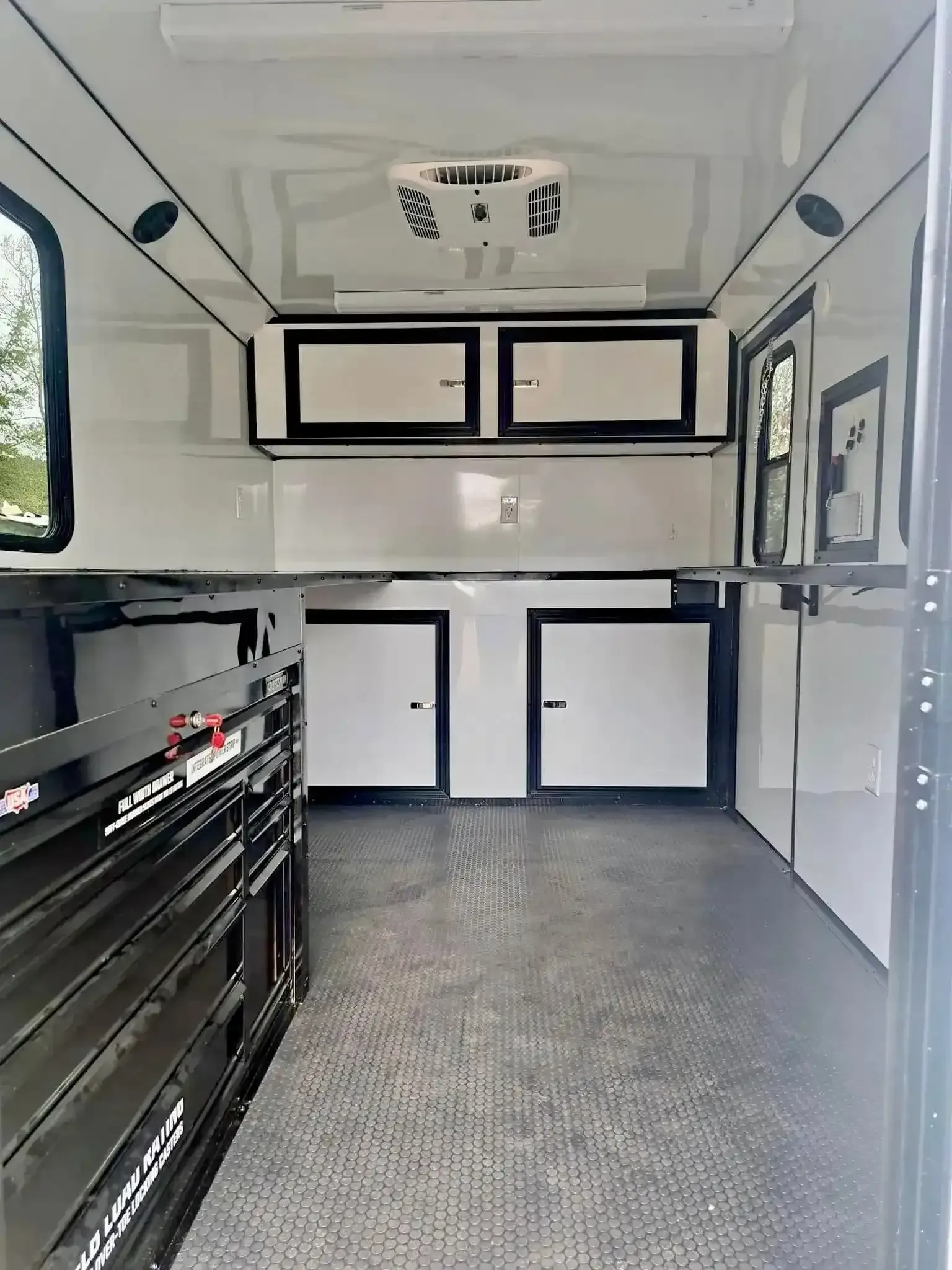 The inside of a trailer with black and white cabinets and a ceiling fan.