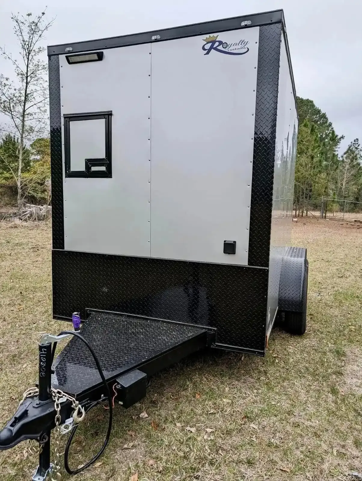 A black and white trailer is parked in a grassy field.