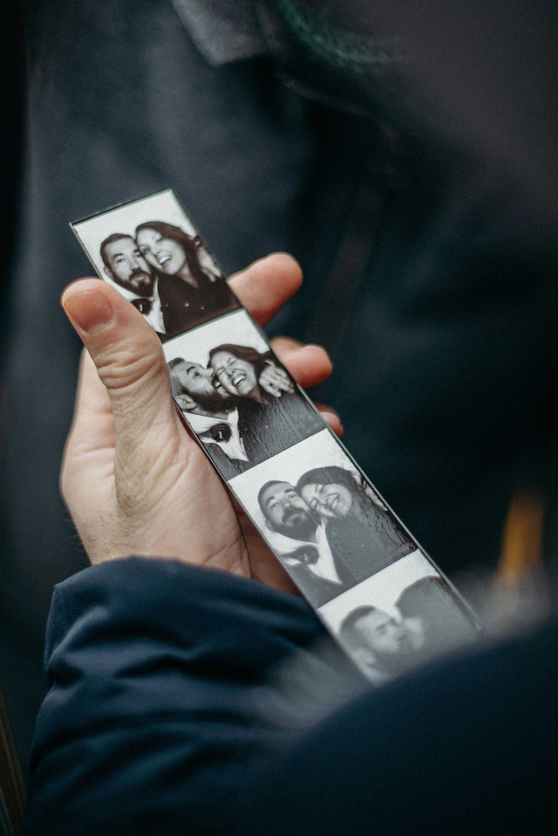 Hand holding a black and white photo strip featuring candid shots of a couple.