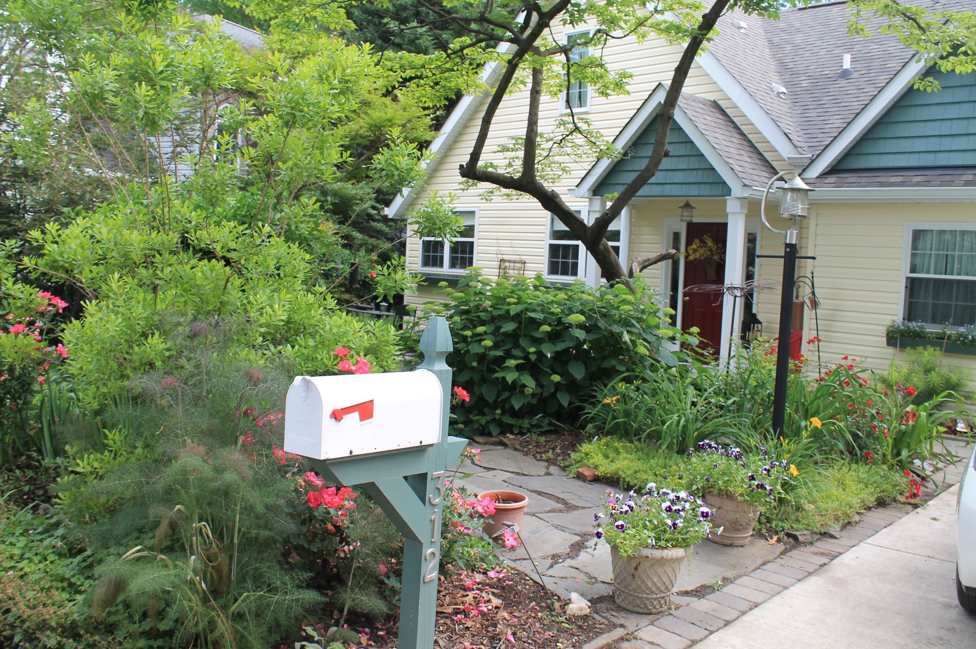 A white mailbox with the letter p on it is in front of a house.