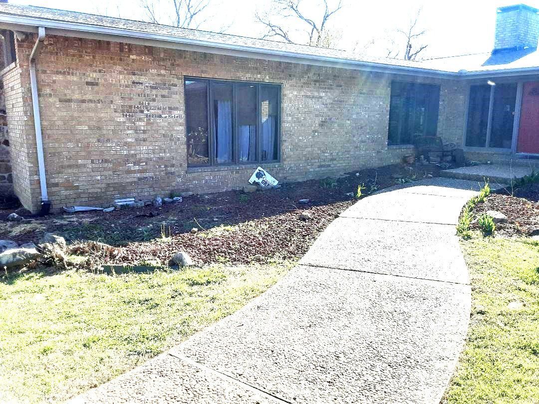 A brick house with a concrete walkway leading to it.