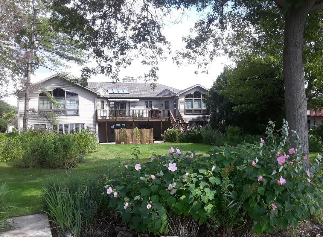 A large house is surrounded by trees and flowers