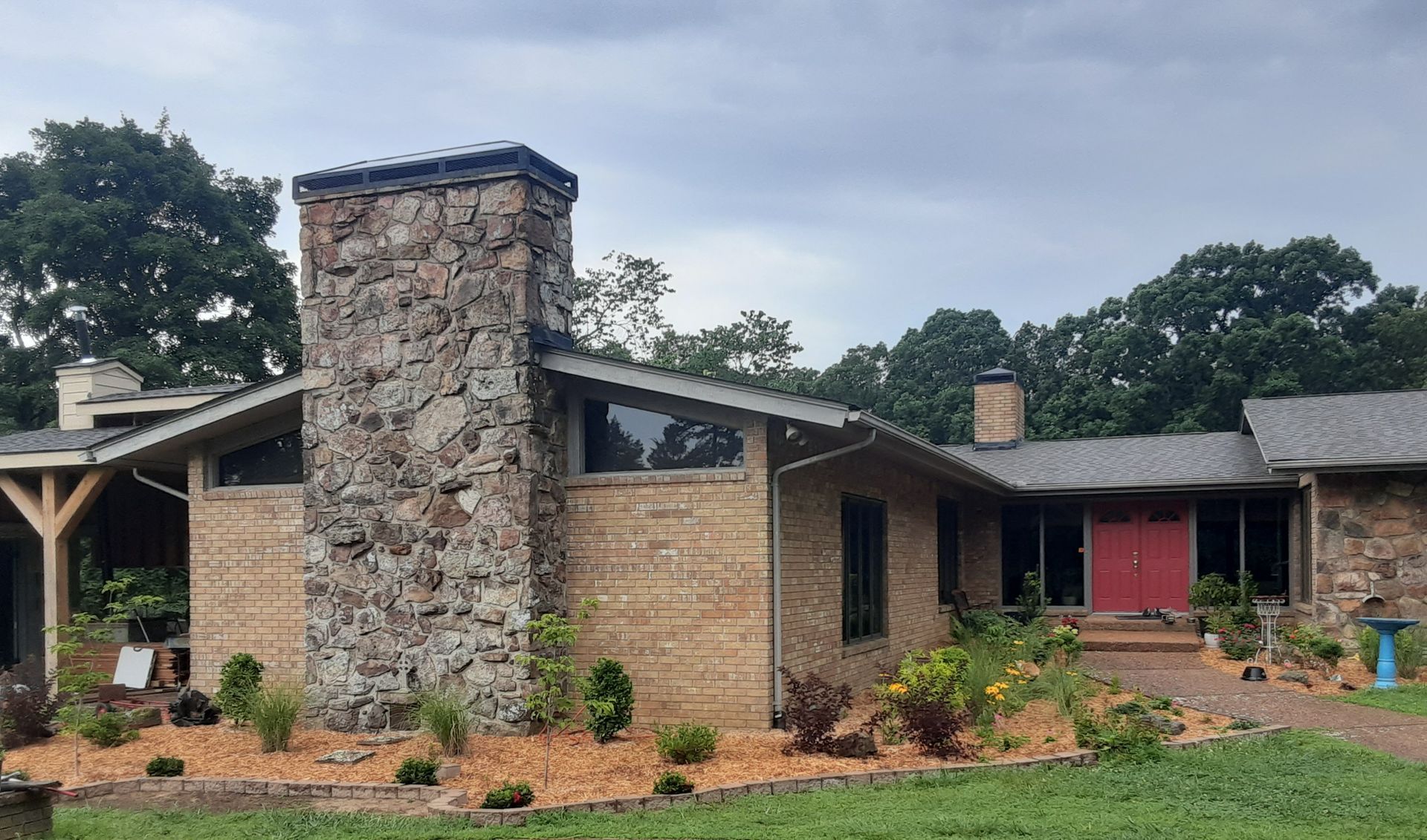 A large brick house with a stone chimney and a red door