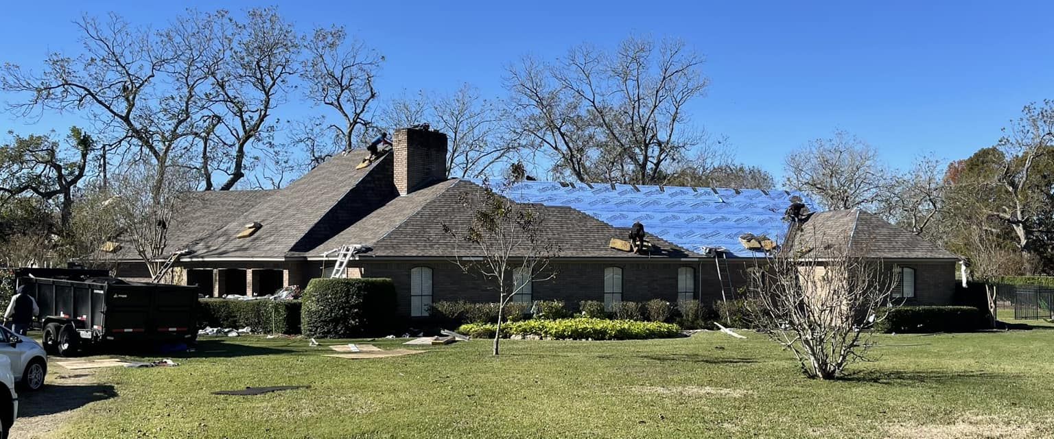 Exterior of a house with a dark gray roof, chimney, and surrounding trees; a white truck is in the left corner.
