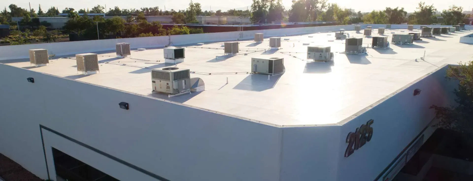 Exterior shot of a white commercial building roof with HVAC units.