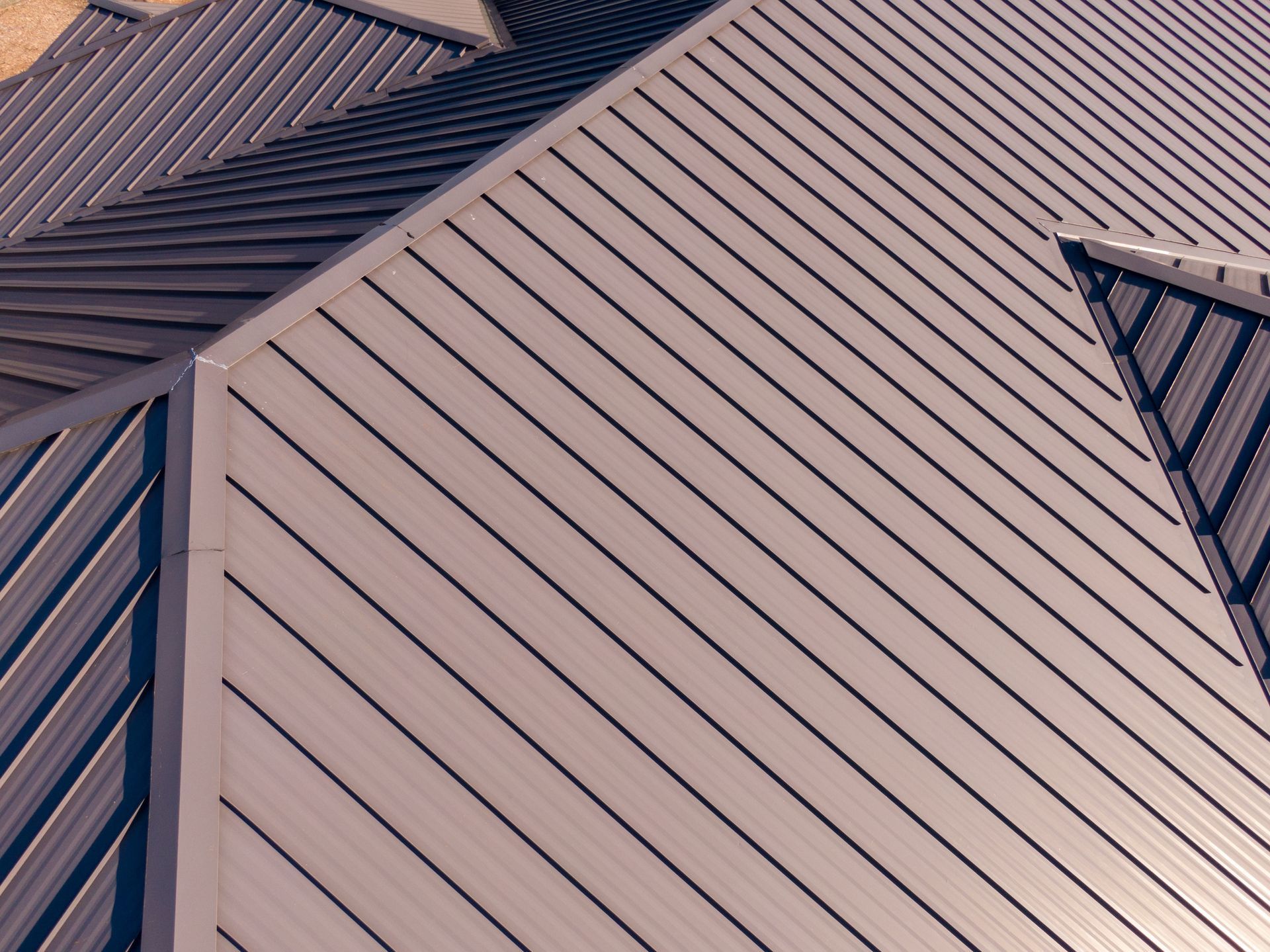 Overhead view of a gray metal roof with diagonal lines and a sharp angle.