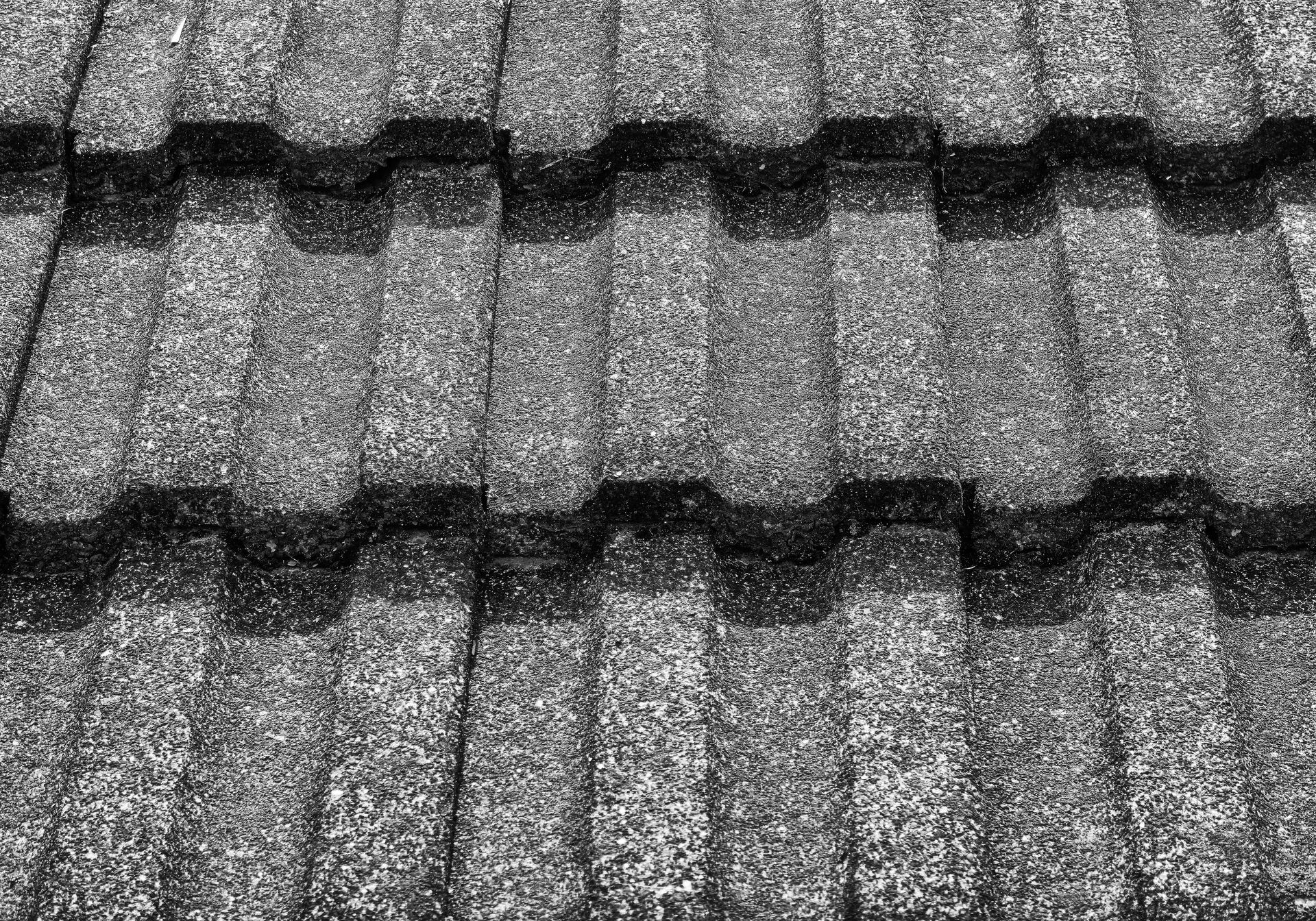 Close-up of a textured, dark gray metal roof with a wavy, interlocking pattern.