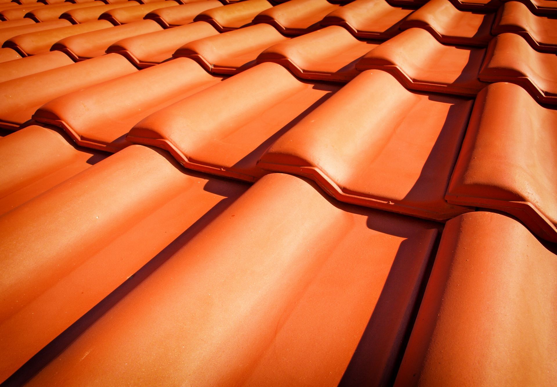 Orange terracotta roof tiles in a close-up, angled view.