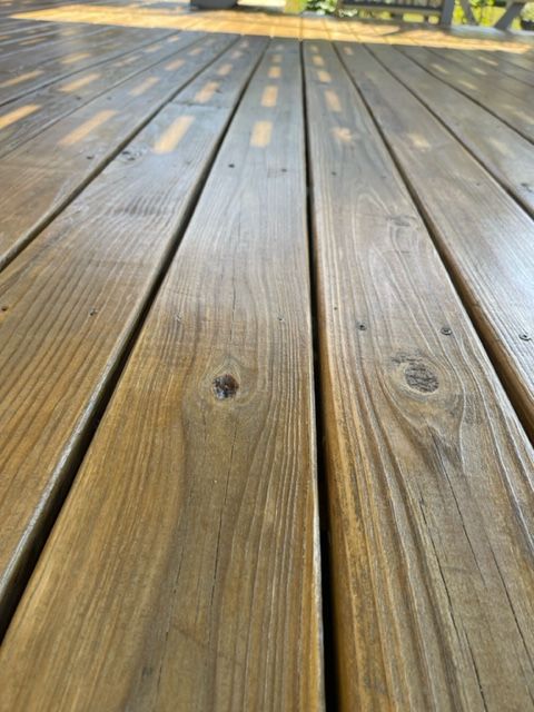 a close up of a wooden deck with a bench in the background .