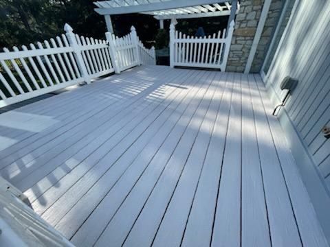 a white deck with a white picket fence and a pergola .