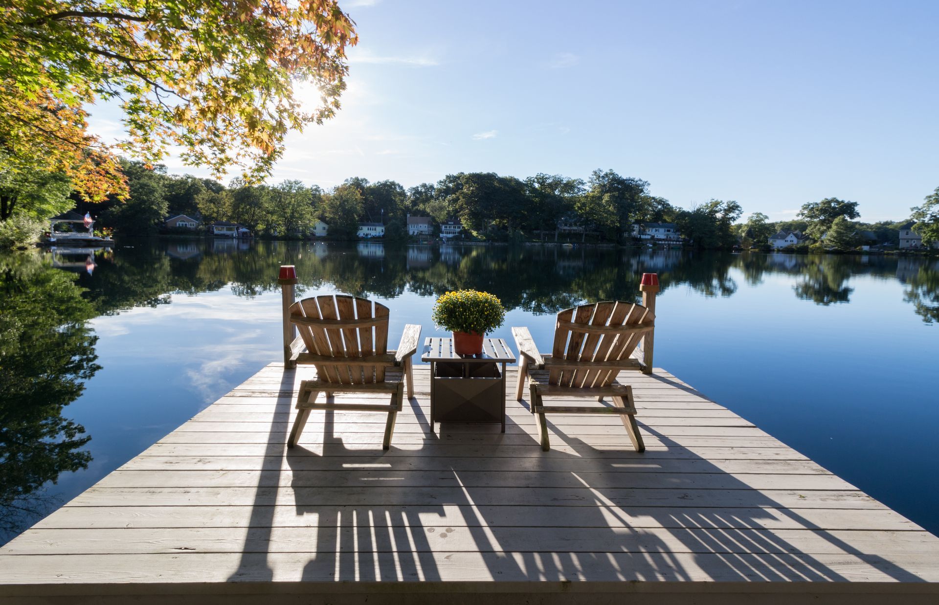 two chairs are sitting on a dock overlooking a lake .